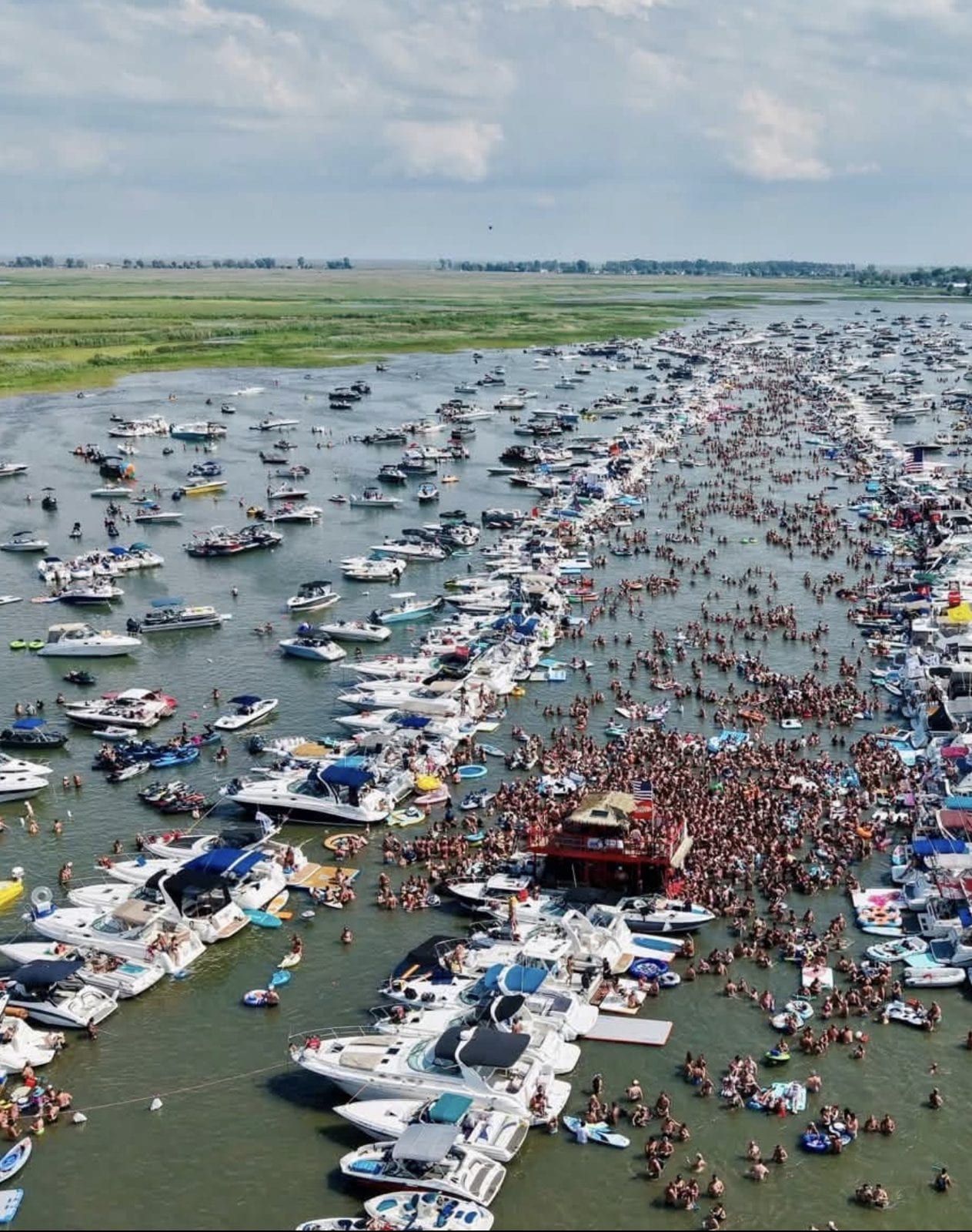 Hundreds of boats rafted up in a long line, a red tiki barge in the middle