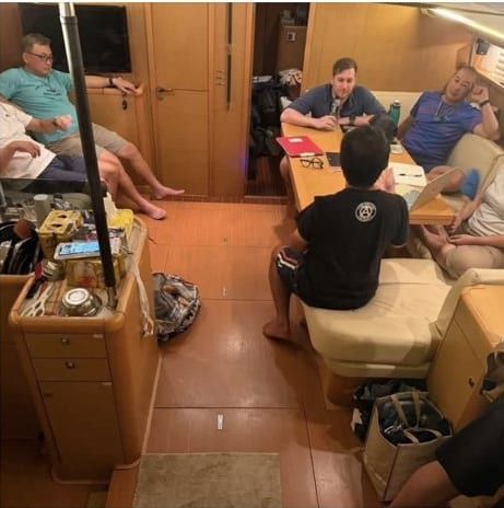 The crew below deck in the saloon of a sailing yacht